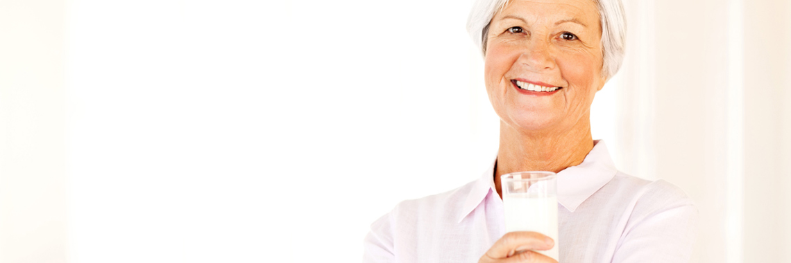 Older woman smiling and holding a glass of milk - Special Nutrition - AAK