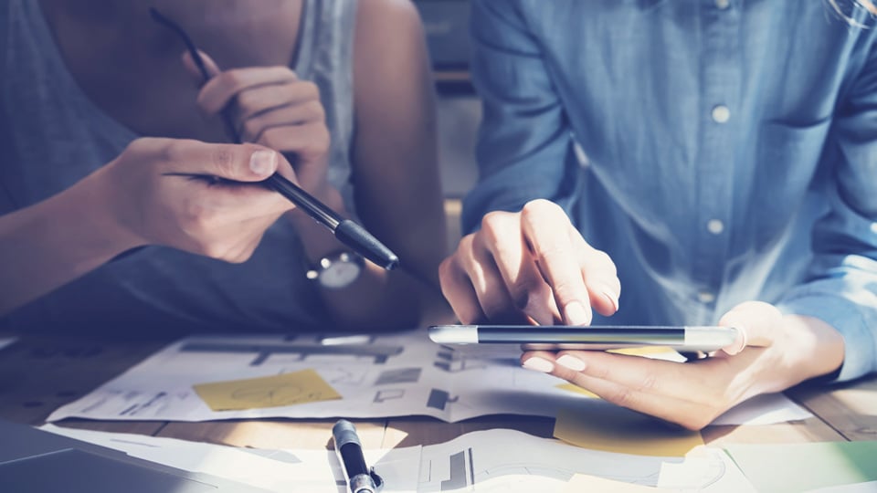 Två kvinnliga kollegor med surfplatta och finansiella dokument - Investerare - AAK