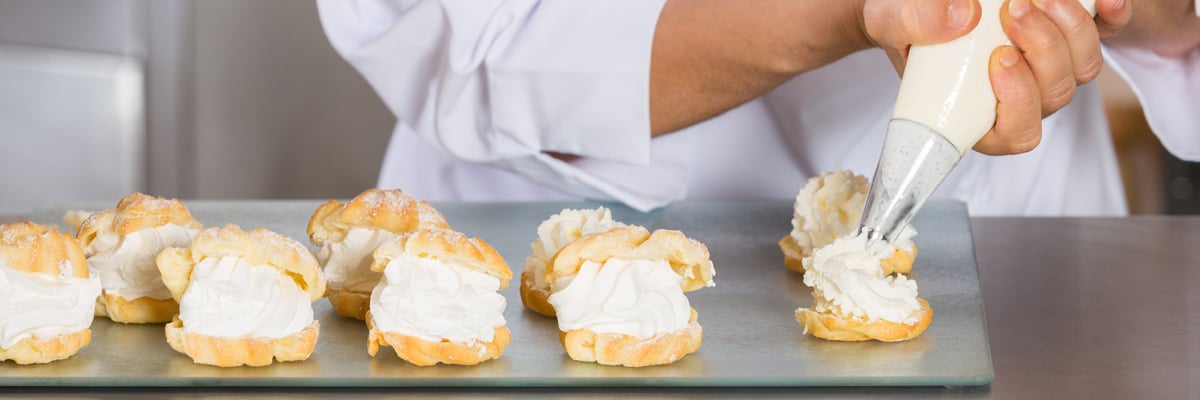 En bagare som spritsar grädde på bakelser - Mejeriprodukter och glass - AAK