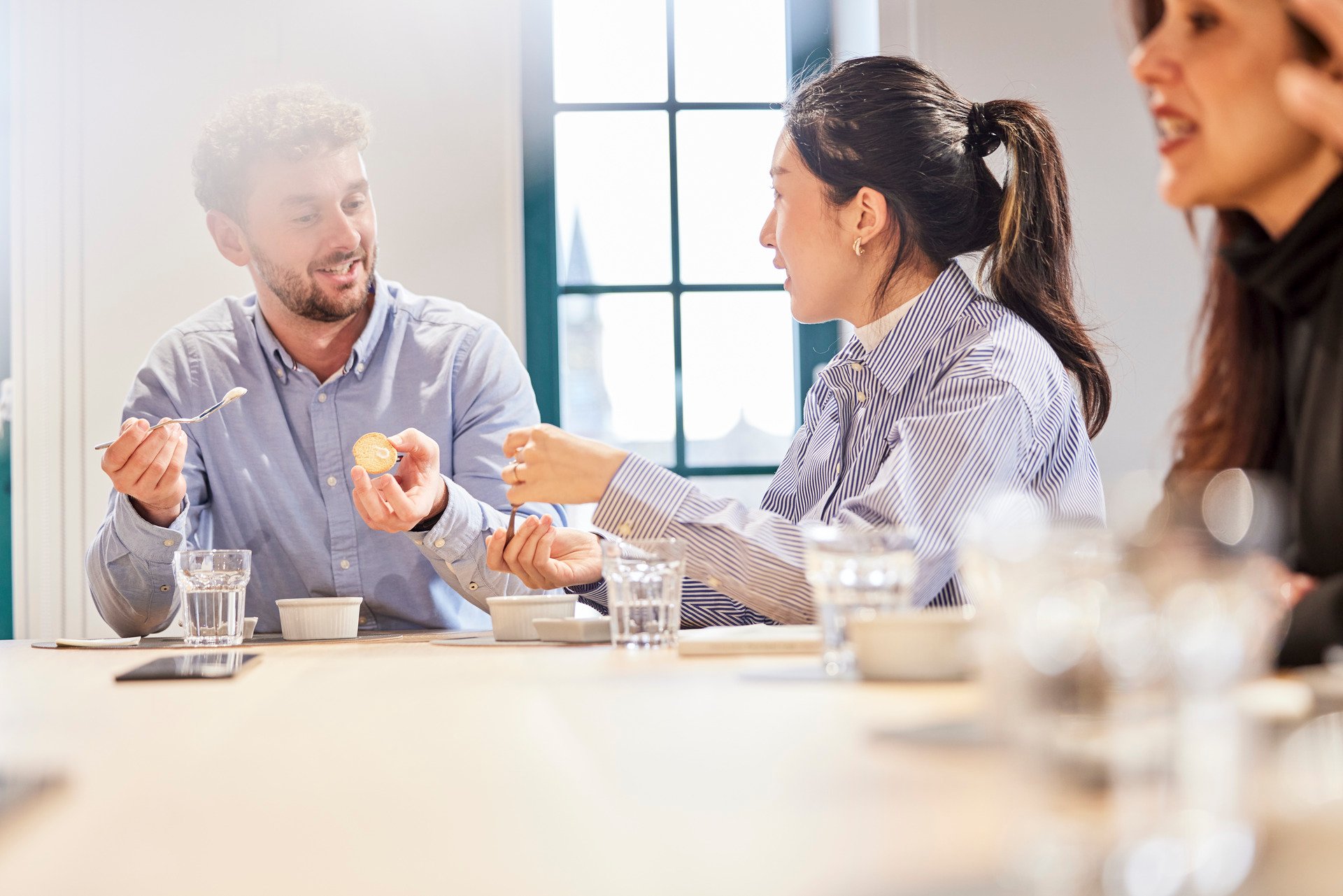 Employees sitting in an AAK meeting room, casually interacting around a table.