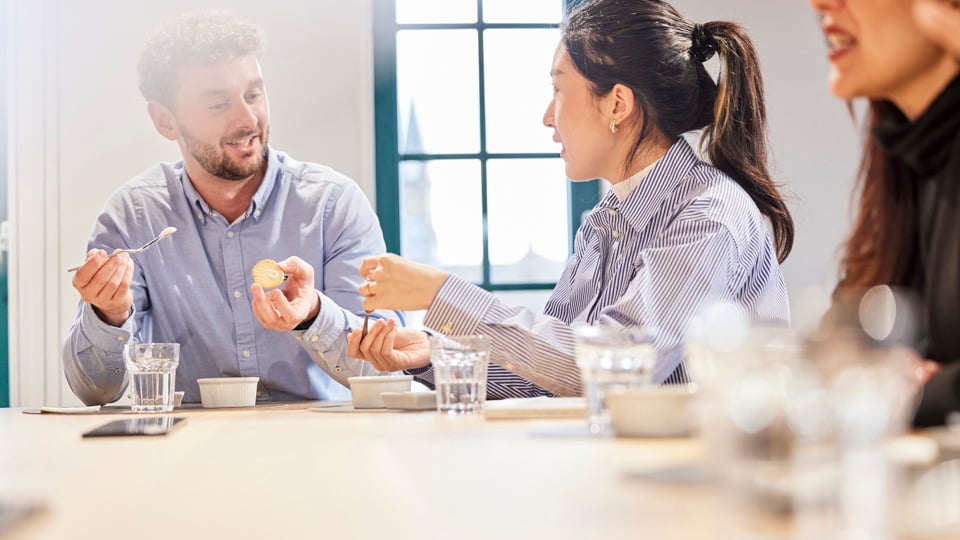 Employees sitting in an AAK meeting room, casually interacting around a table.