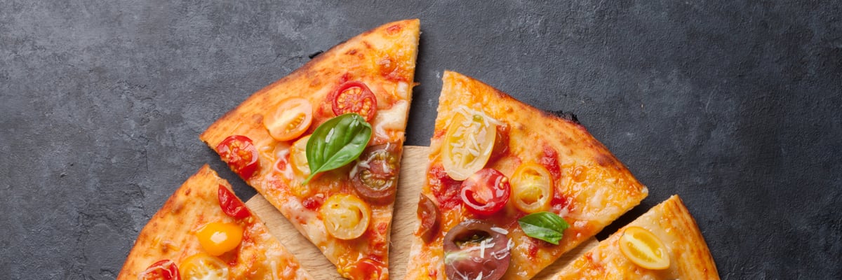 Basilika och tomat på läcker pizza som ligger på ett marmorbord - Bageri - AAK