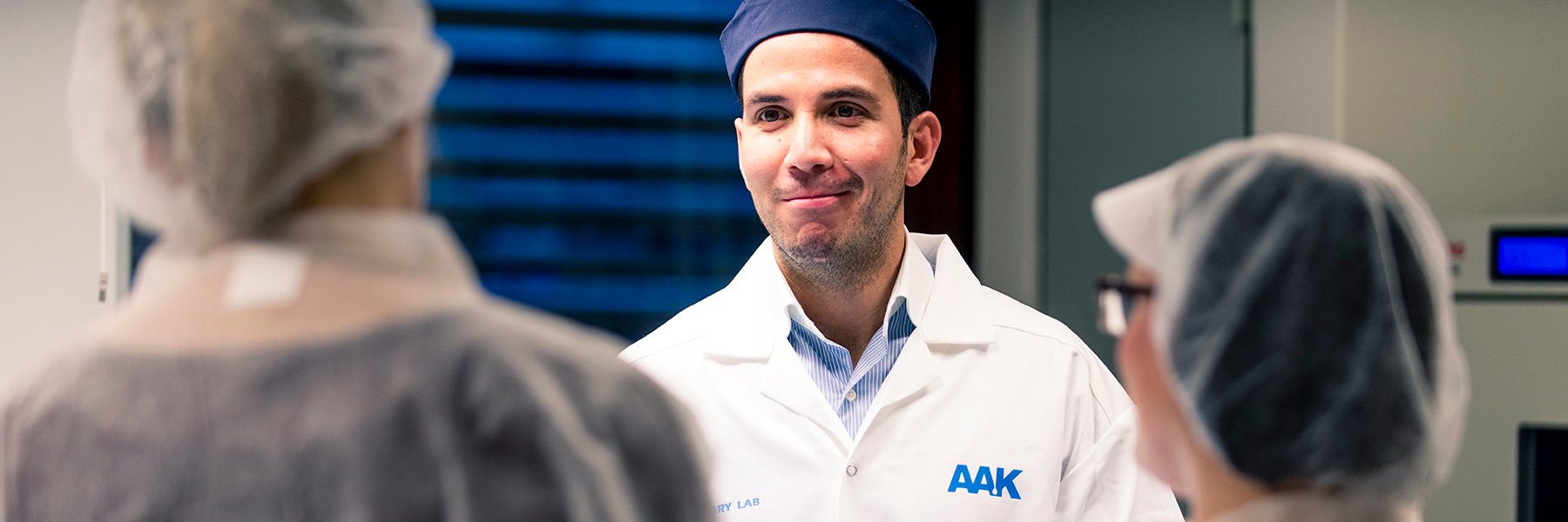 AAK staff wearing an AAK lab coat and blue cap.