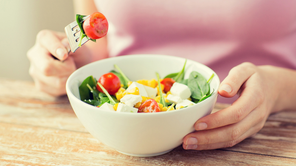 Woman in front a bowl of vegetables and feta cheese - Special Nutrition - AAK