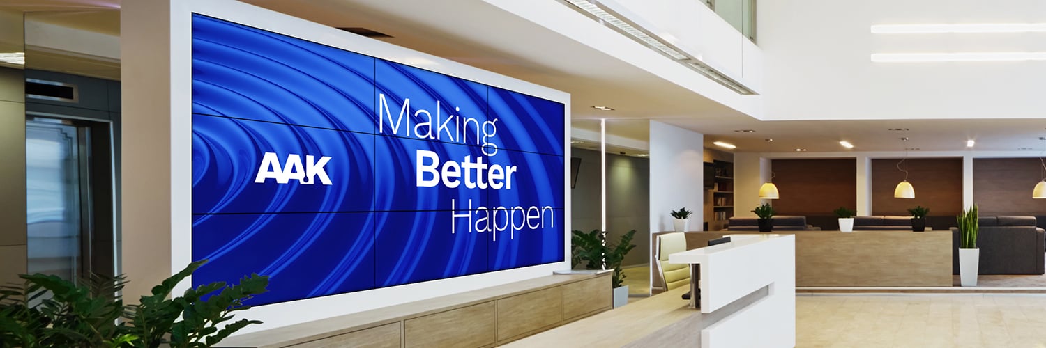 Modern office lobby with a digital screen reading 'AAK Making Better Happen,'