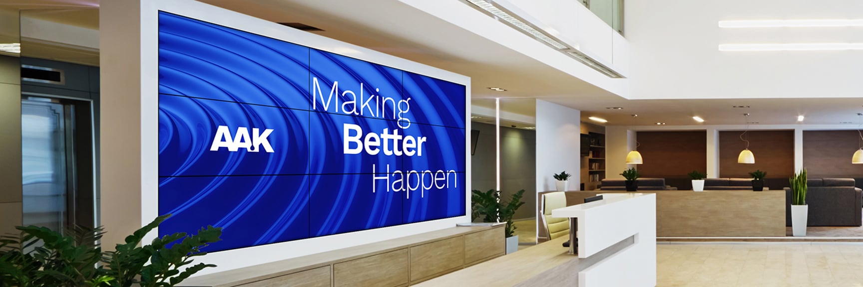Modern office lobby with a digital screen reading 'AAK Making Better Happen,'