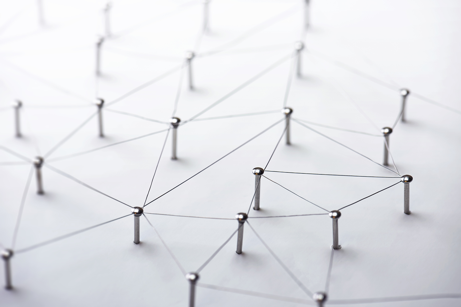 Network of metal pins connected by thin strings, forming a geometric pattern on a flat surface.
