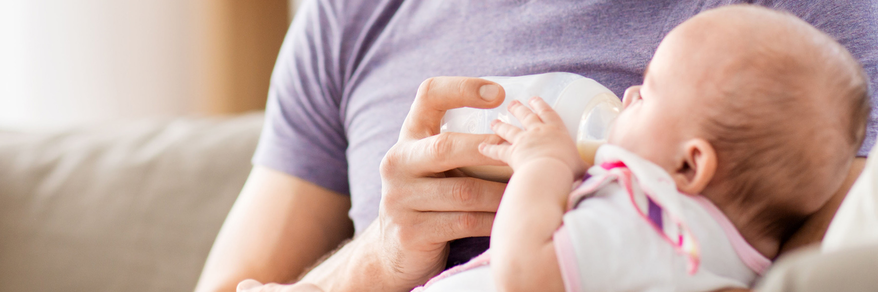 Man feeding a baby formula in a bottle.