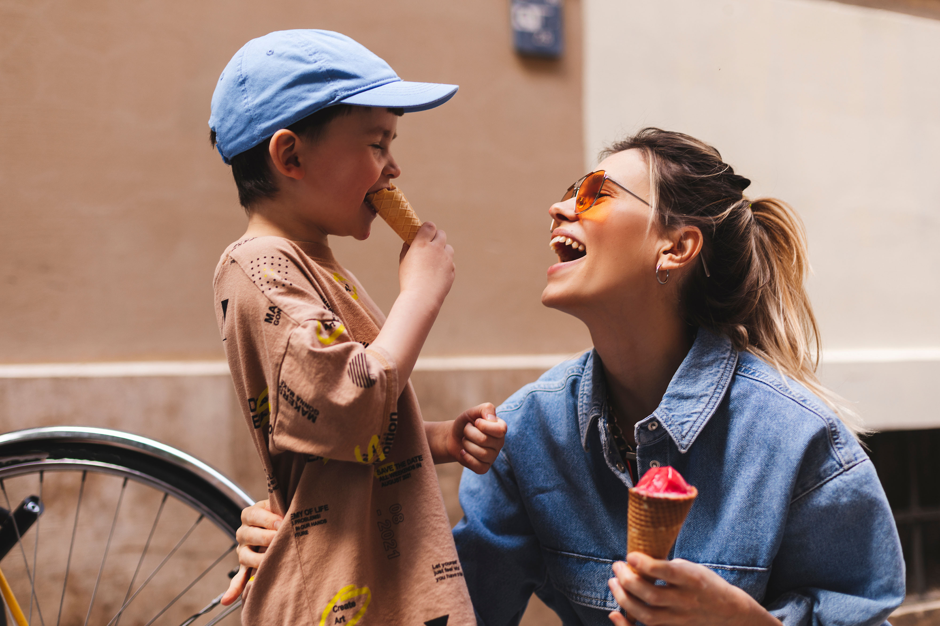 Child and adult enjoying ice cream together outdoors.