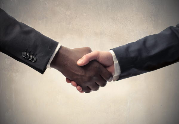 Close up of two people in suits shaking hands.