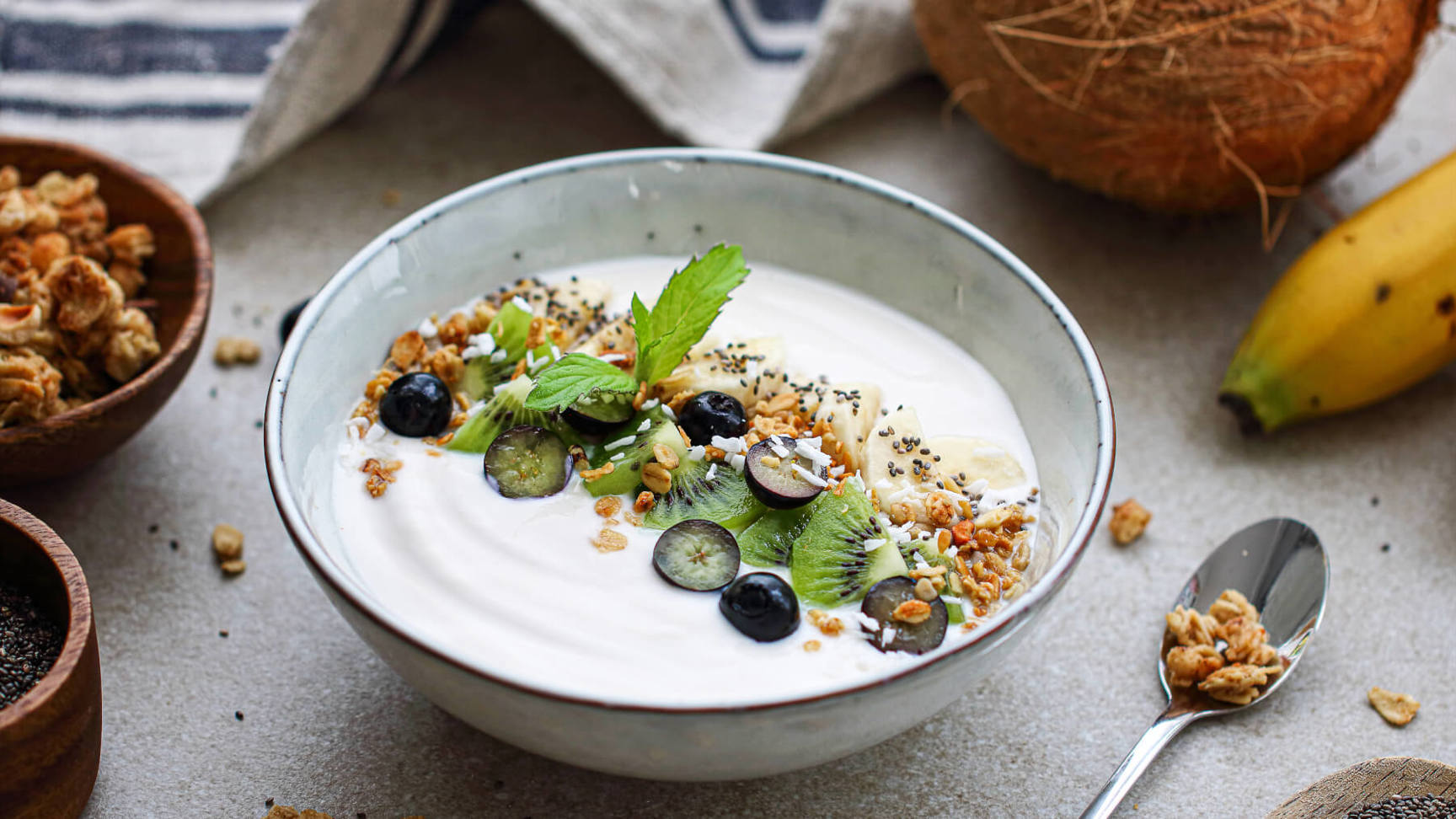 A bowl of yogurt made with plant based dairy topped with fresh berries and crunchy granola, showcasing a colorful and healthy breakfast option.