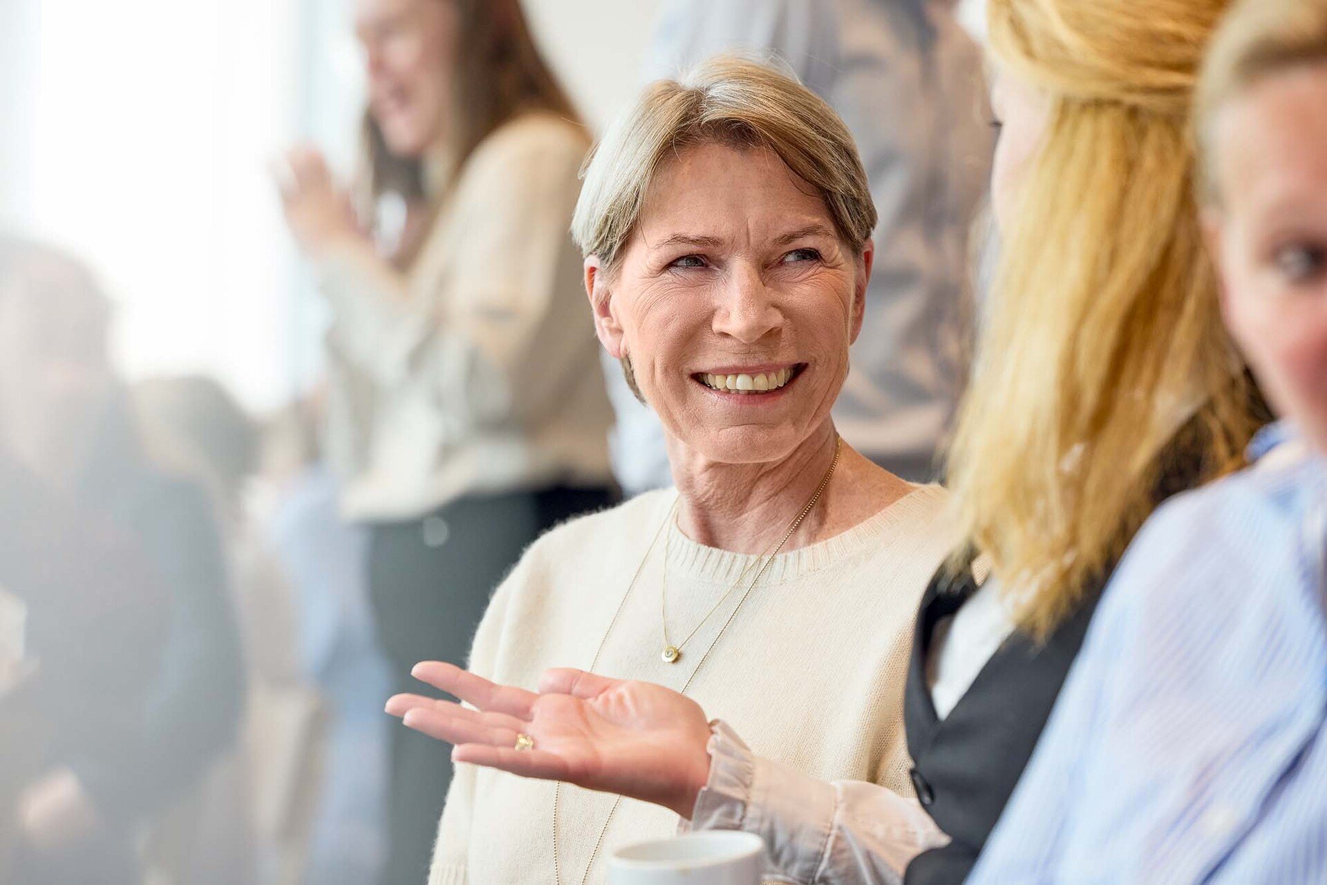 Two AAK employees engaged in conversation during a meeting or event, with a coffee cup visible in the foreground
