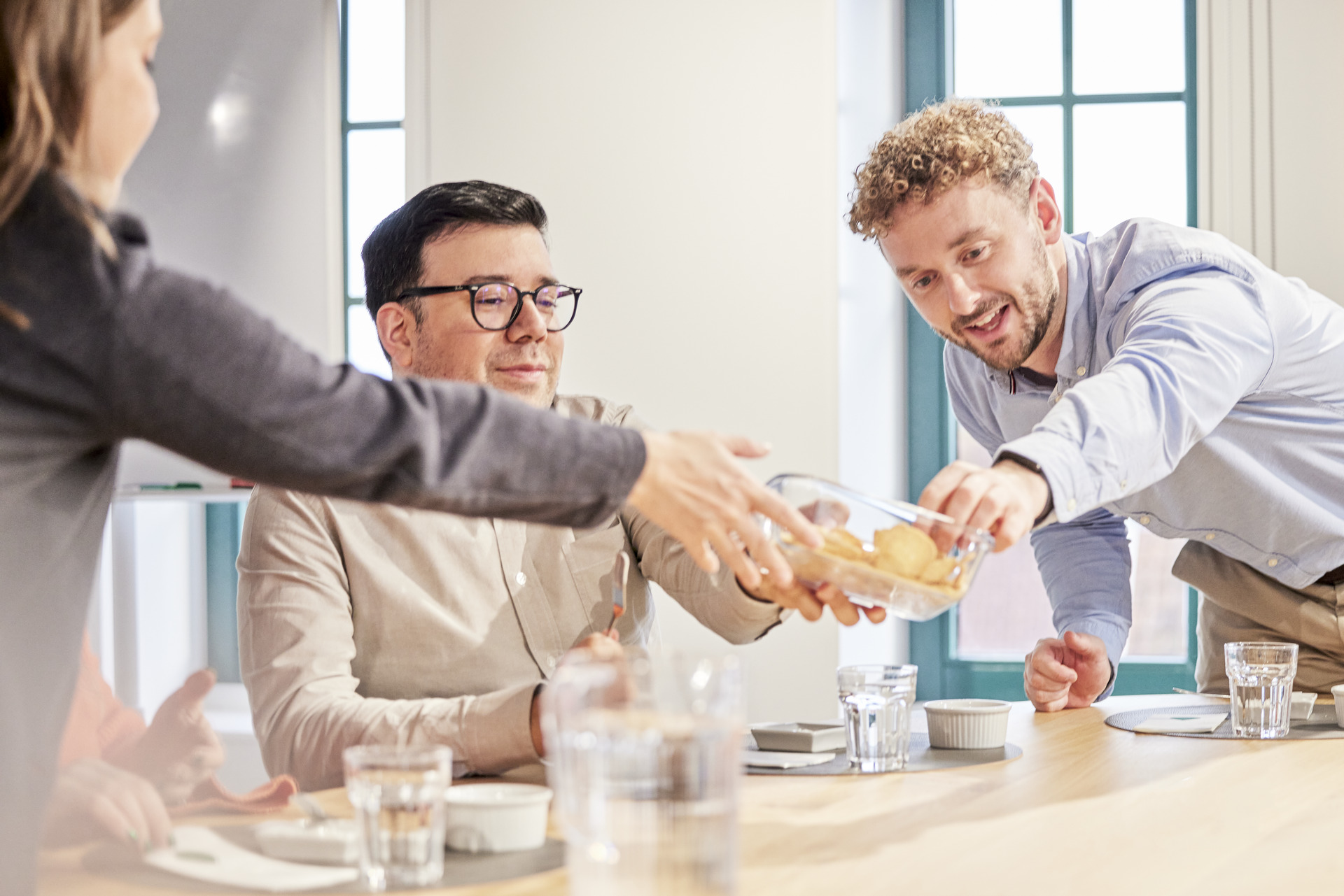 Group of AAK employees around a table sharing baked goods during a tasting session, with glasses and plates arranged neatly