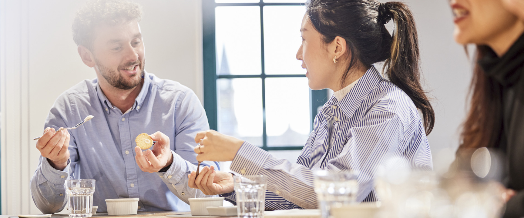 Employees sitting in an AAK meeting room, casually interacting around a table.