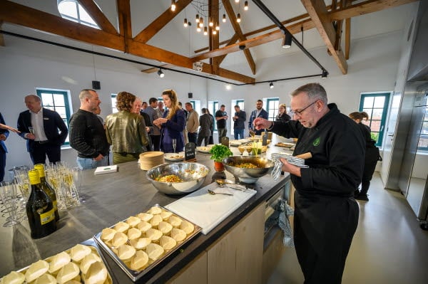 A group of people socializing around a table filled with various food and drinks.