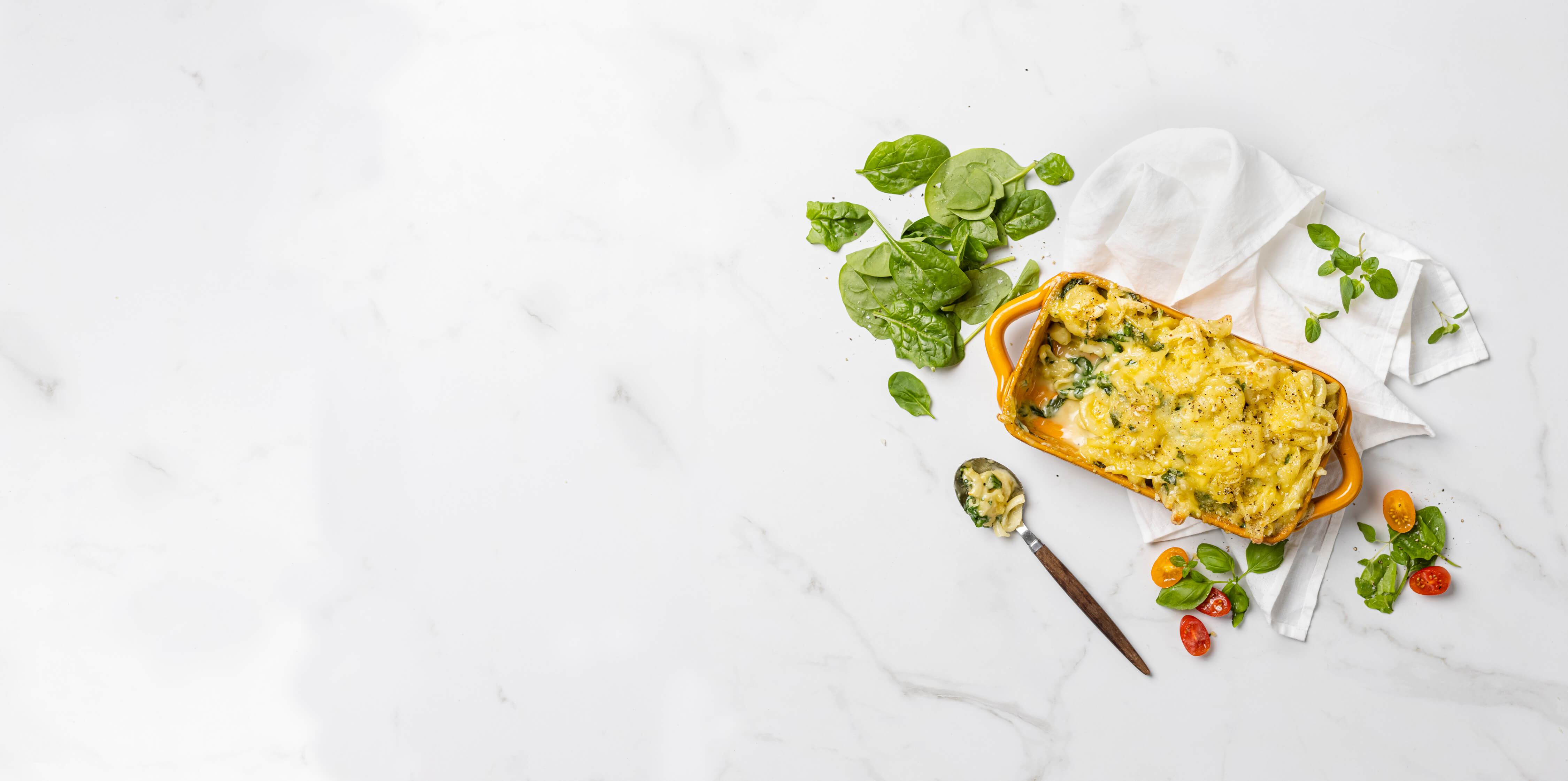 A plant-based casserole dish filled with colorful vegetables and fresh herbs, placed on a polished marble surface.