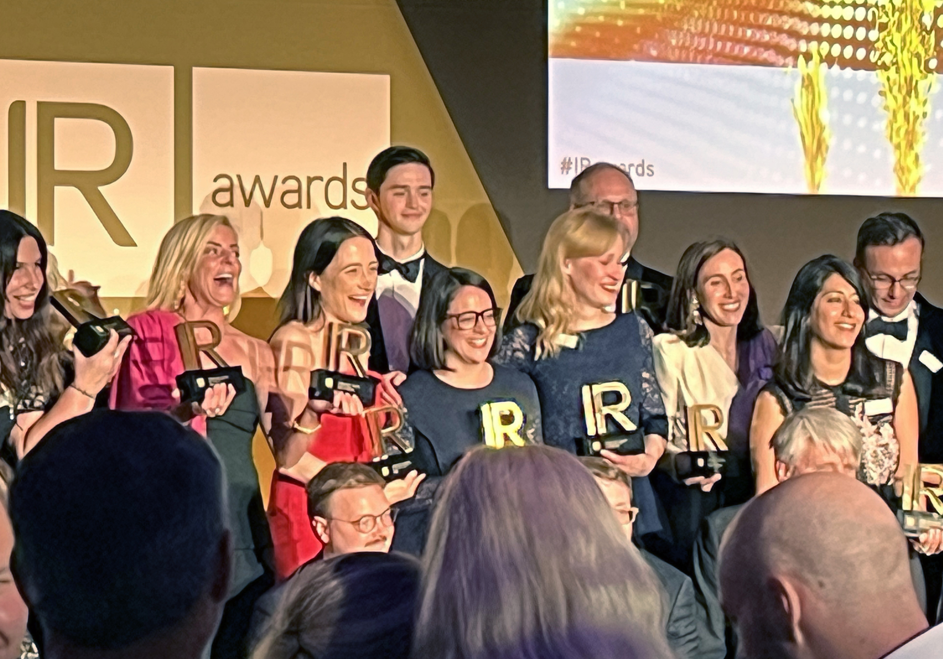 Group of people holding IR-shaped trophies at an IR awards event.