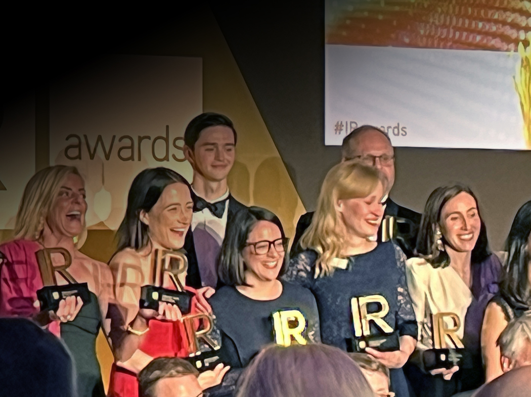 Group of people holding IR-shaped trophies at an IR awards event.