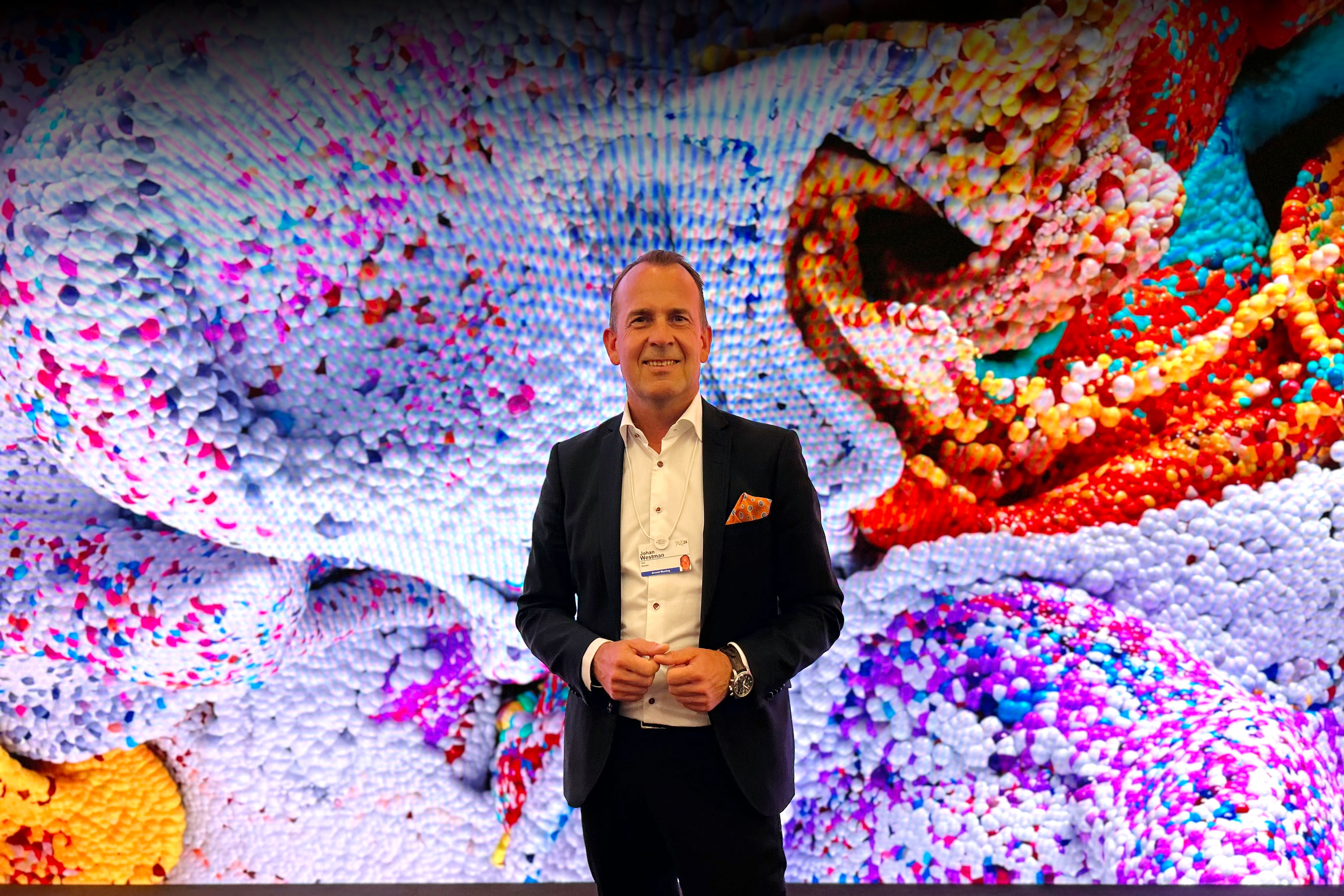 CEO, Johan Westman smiling on a stage in front of a big colorful screen