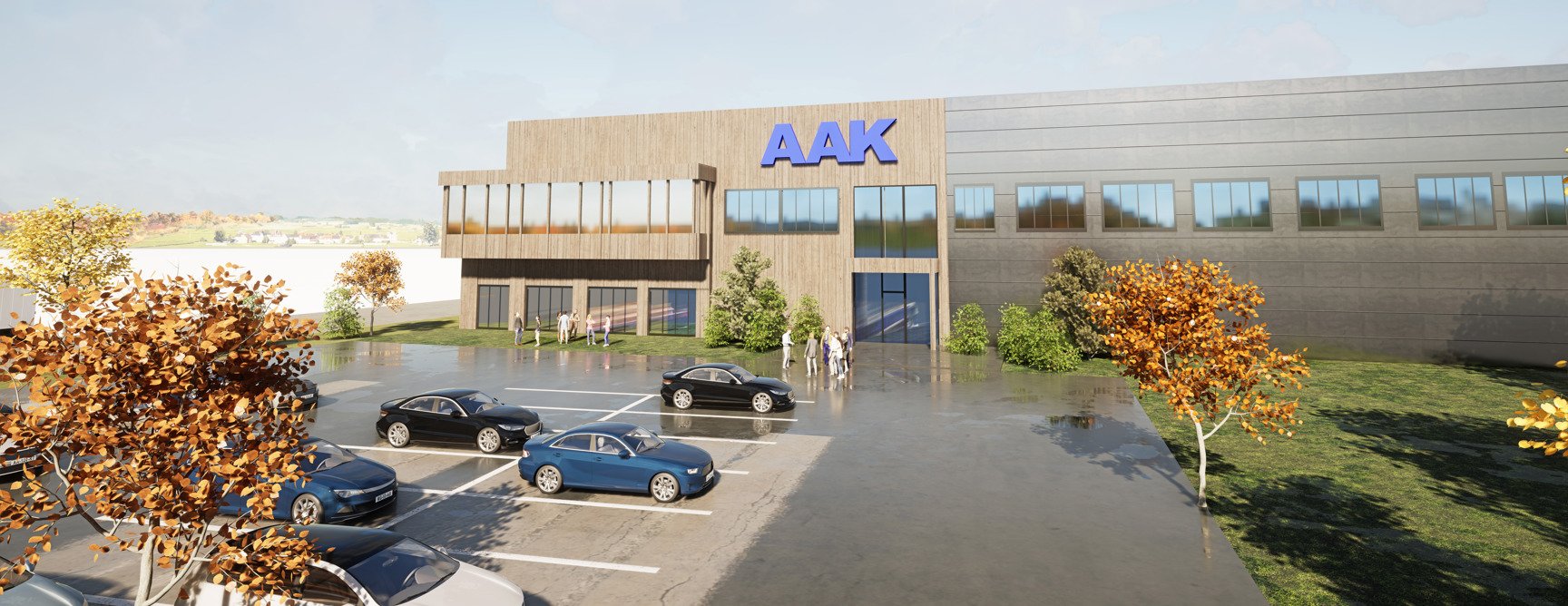 Ny modern anläggning med "AAK" på fasaden, omgiven av höstträd, parkerade bilar och människor vid ingången.