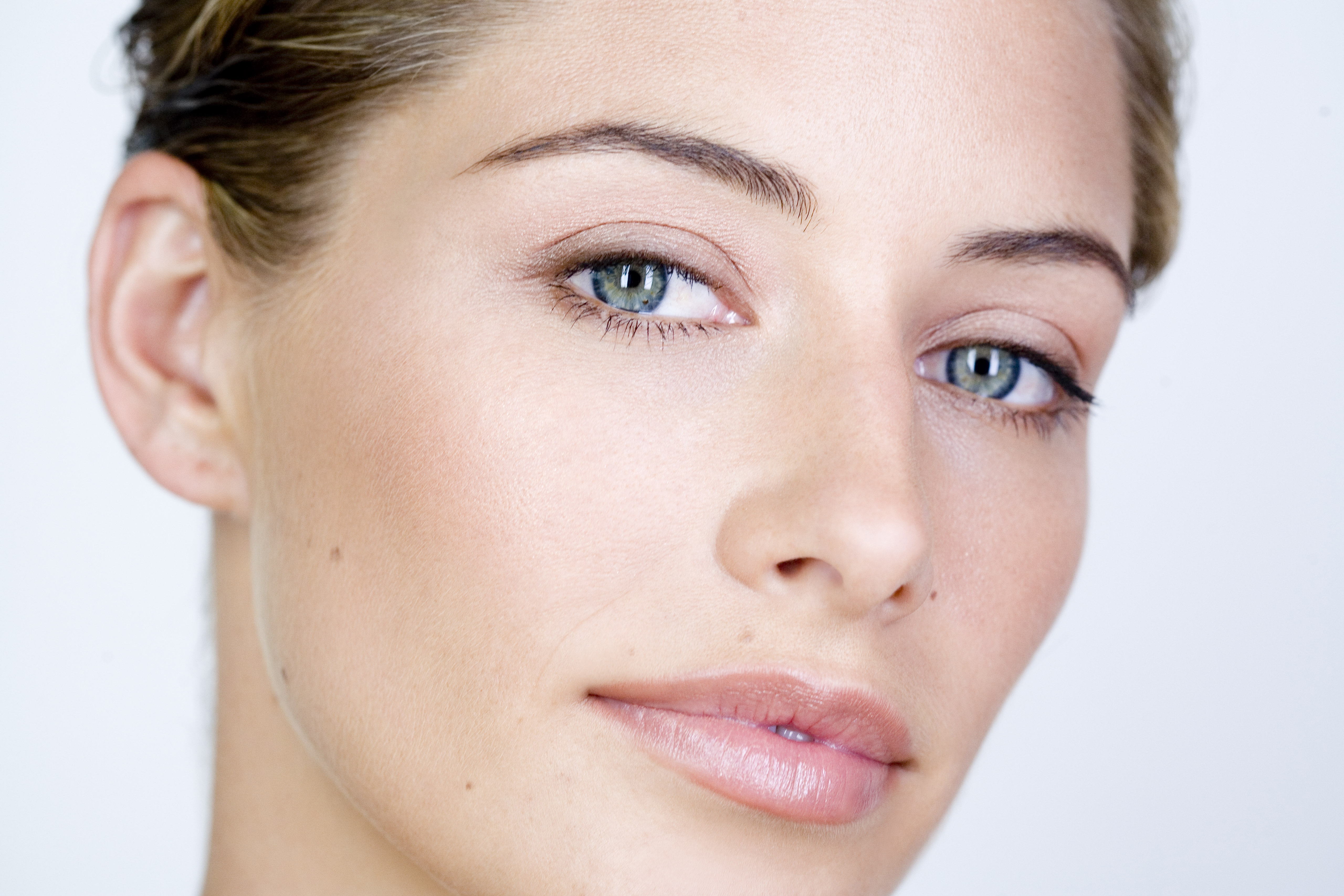 Close up of a woman with clear skin and bright background.