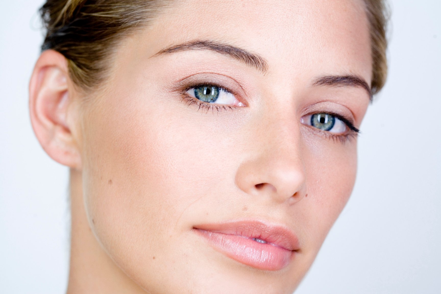 Close up of a woman with clear skin and bright background.