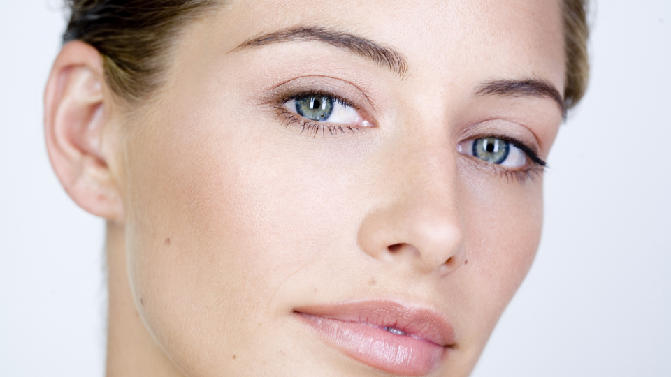 Close up of a woman with clear skin and bright background.